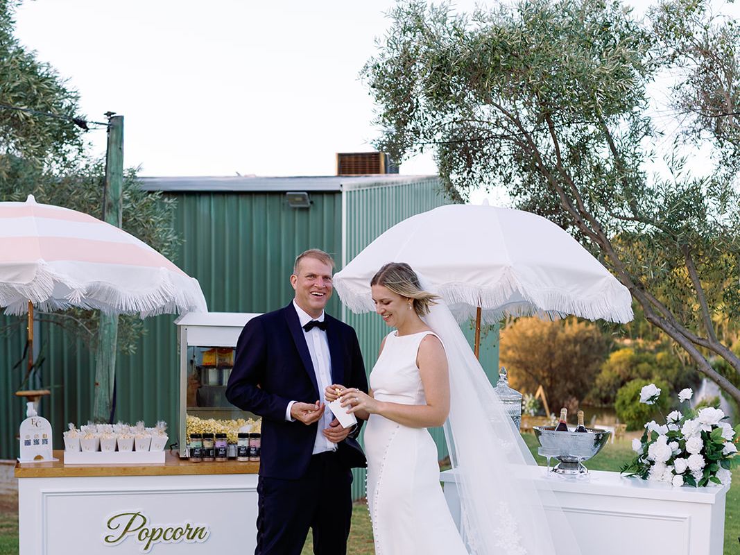 Bride and groom at popcorn and drinks carts at their wedding